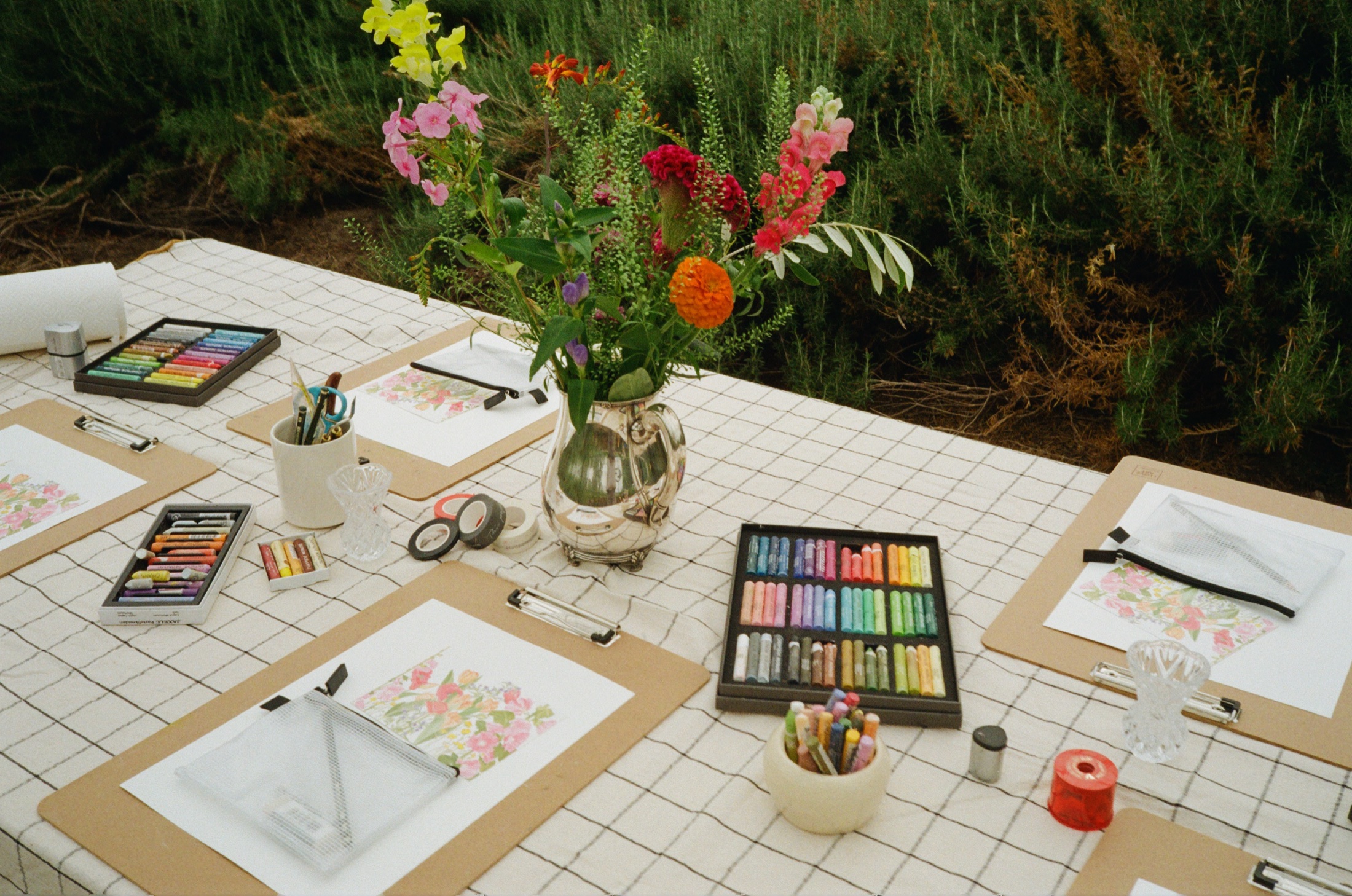 Vorbereiteter Workshoptisch mit Blumen und Ölpastellkreiden
